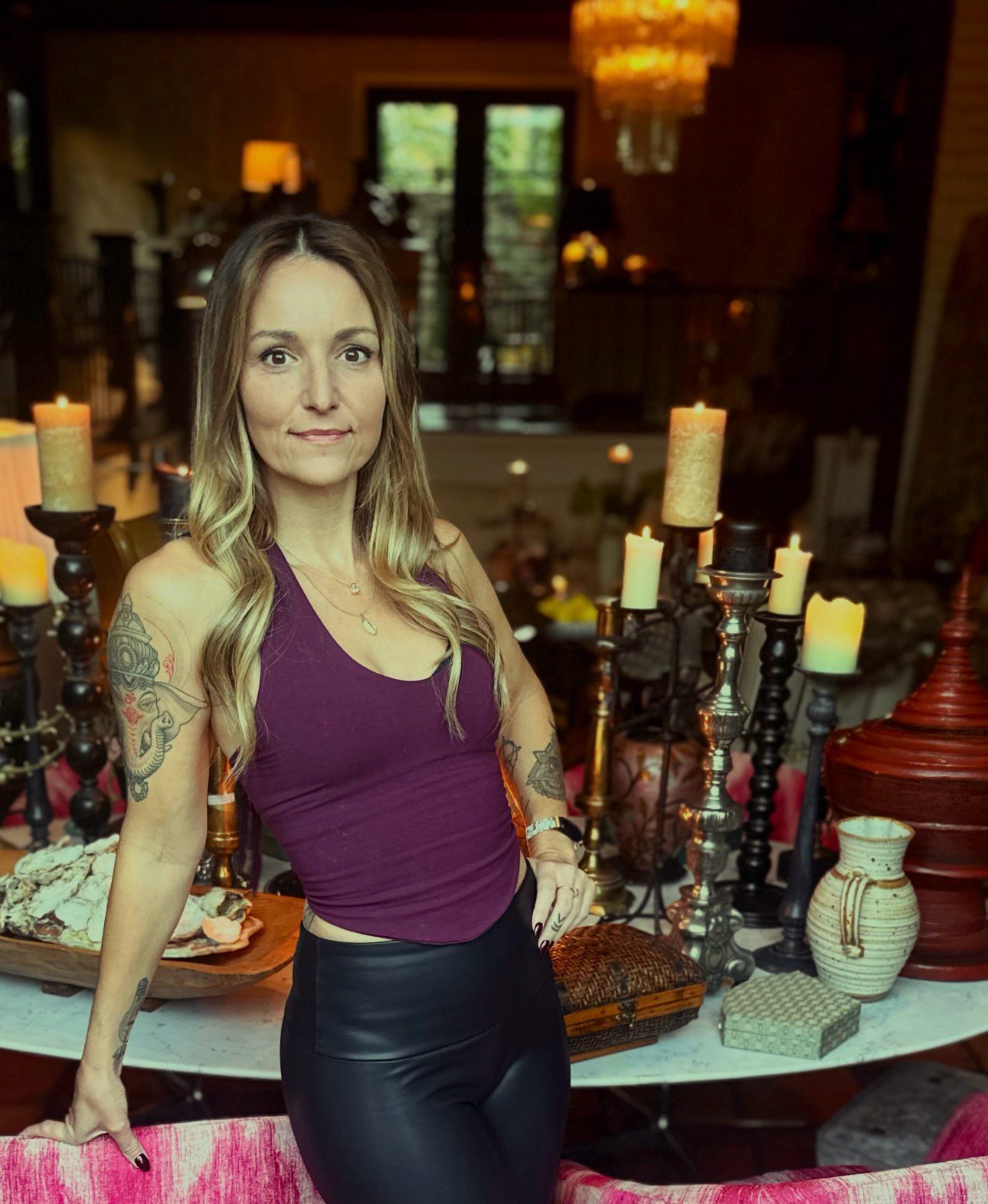 Kayla smiling in a warm, candlelit room surrounded by candles and treasures